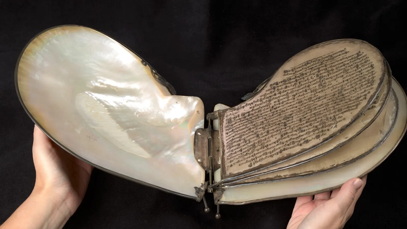 Pétition birmane gravée sur des feuilles de nacre reliées, tenues à deux mains